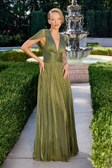 Woman in a green evening gown standing in front of a fountain with manicured hedges.