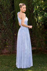 Woman in a light blue dress standing outdoors with greenery in the background