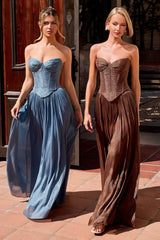 Two women modeling strapless corset maxi gowns outdoors. The woman on the left wears a dusty blue gown, and the woman on the right wears a brown gown.