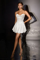 Model wearing a white dress on a dark runway