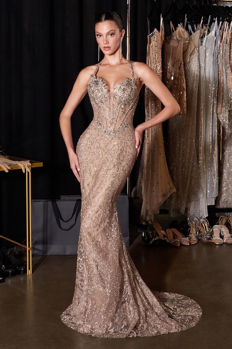 Woman in a sparkling evening gown standing in front of a rack of dresses.