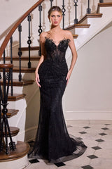 Woman in a black evening gown standing in front of a staircase.