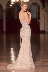 Woman in a glamorous evening gown with intricate detailing in an elegant indoor setting.