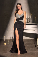 Woman in a black evening gown with a high slit standing in front of a piano and candles.