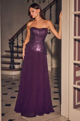 A woman models a strapless formal gown with a sparkling purple sequined bodice and a flowing chiffon skirt, standing in a doorway next to a staircase.