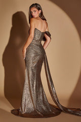A woman modeling a strapless metallic bronze gown with a sweetheart neckline, off-the-shoulder sleeves, and a long draped train against a warm beige studio backdrop with dramatic lighting.