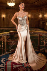 dress features an embellished, corset-style bodice with intricate silver detailing and a softly draped skirt that flows into a long train.