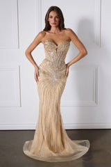 Woman wearing a strapless, beaded evening gown against a white paneled wall.