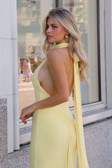 Woman in a yellow dress standing outdoors near a building.