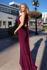 Woman in a burgundy evening gown standing on a city street.
