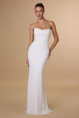 Woman wearing a strapless white evening gown against a beige background