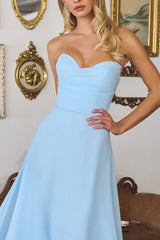Woman wearing a light blue strapless dress in an elegant room with gold-framed mirrors.