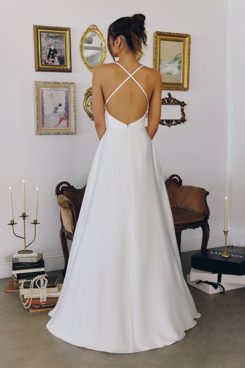 Model wearing a satin gown with draped cowl neckline, fitted waist, and floor-length skirt, featuring thin crisscross straps and open back