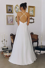 Model wearing a satin gown with draped cowl neckline, fitted waist, and floor-length skirt, featuring thin crisscross straps and open back
