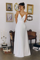 Model wearing a satin gown with draped cowl neckline, fitted waist, and floor-length skirt, featuring thin crisscross straps and open back