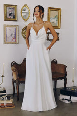 Model wearing a satin gown with draped cowl neckline, fitted waist, and floor-length skirt, featuring thin crisscross straps and open back