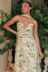 Woman wearing a floral dress standing in front of greenery