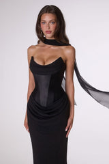Woman wearing a black dress with sheer overlay on a white background