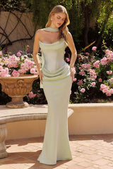 Woman in a light green strapless gown standing in a garden with pink flowers.