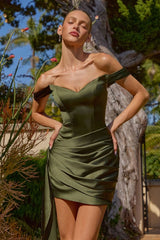 Woman wearing a green dress standing outdoors with plants and trees in the background