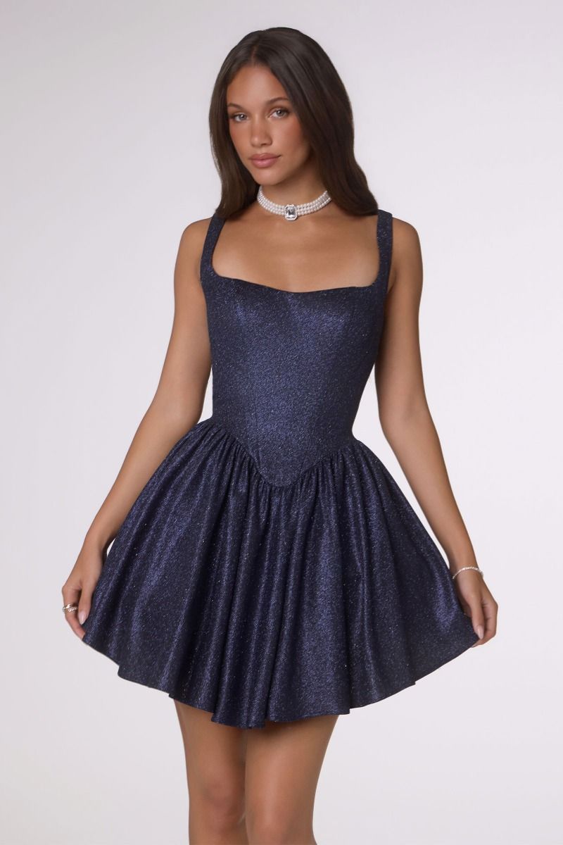 Woman wearing a sparkly navy blue dress on a white background