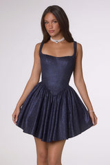Woman wearing a sparkly navy blue dress on a white background