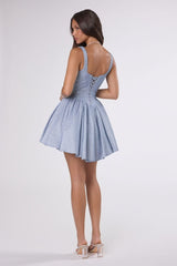 Woman wearing a light blue dress with a button detail on a white background