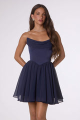 Woman wearing a navy blue strapless dress on a white background