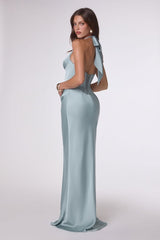 Woman wearing a light blue evening gown with a open back design on a white background