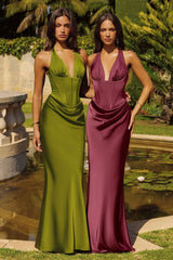 Two women in green and purple evening gowns standing by a pond with greenery.