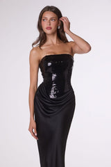 Woman wearing a black strapless gown with sequin detailing on a white background