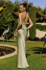 Woman in a green evening gown standing in a garden setting