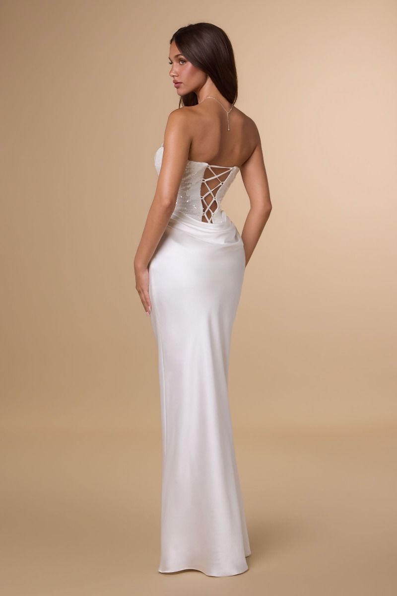 Woman wearing a white strapless gown with lace-up back on a beige background