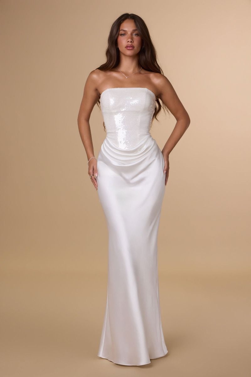 Woman wearing a strapless white gown against a beige background