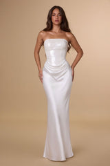 Woman wearing a strapless white gown against a beige background