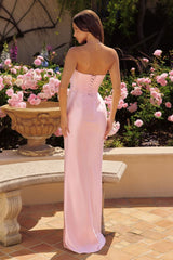 Woman in a pink evening gown standing in front of floral arrangements.