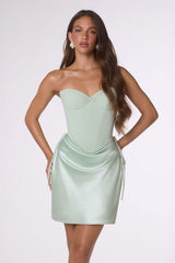 Woman wearing a light green strapless dress against a white background