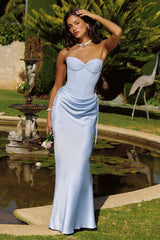 Woman in a light blue strapless gown standing by a pond with garden decorations.