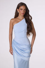 Woman wearing a light blue one-shoulder dress against a white background