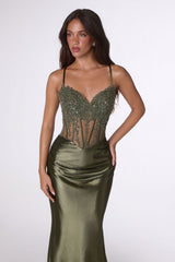 Woman wearing a green evening gown with a beaded bodice on a white background