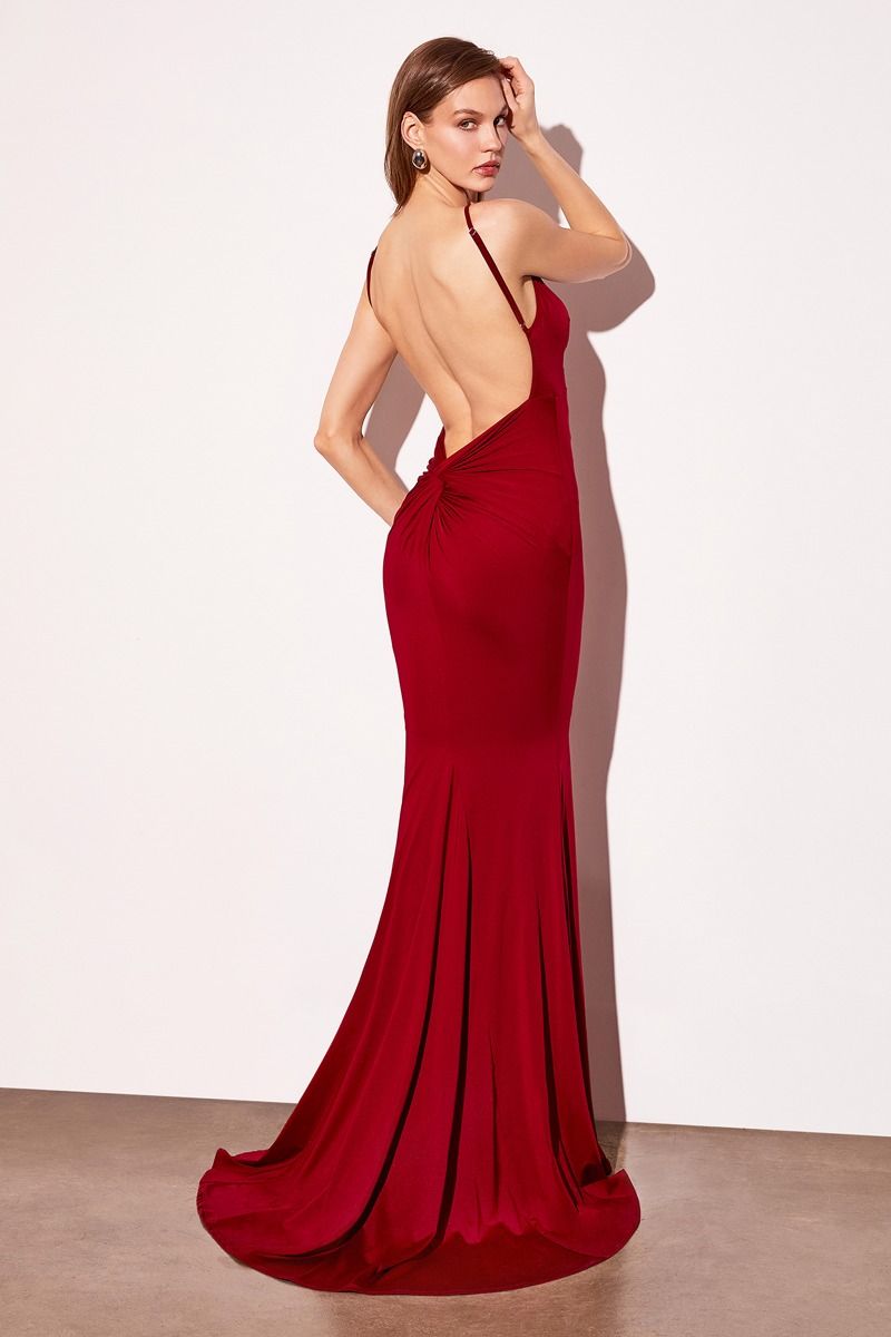 Woman wearing a red evening gown with a high slit on a plain background