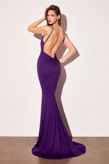 Woman wearing a purple evening gown with a high slit on a plain background
