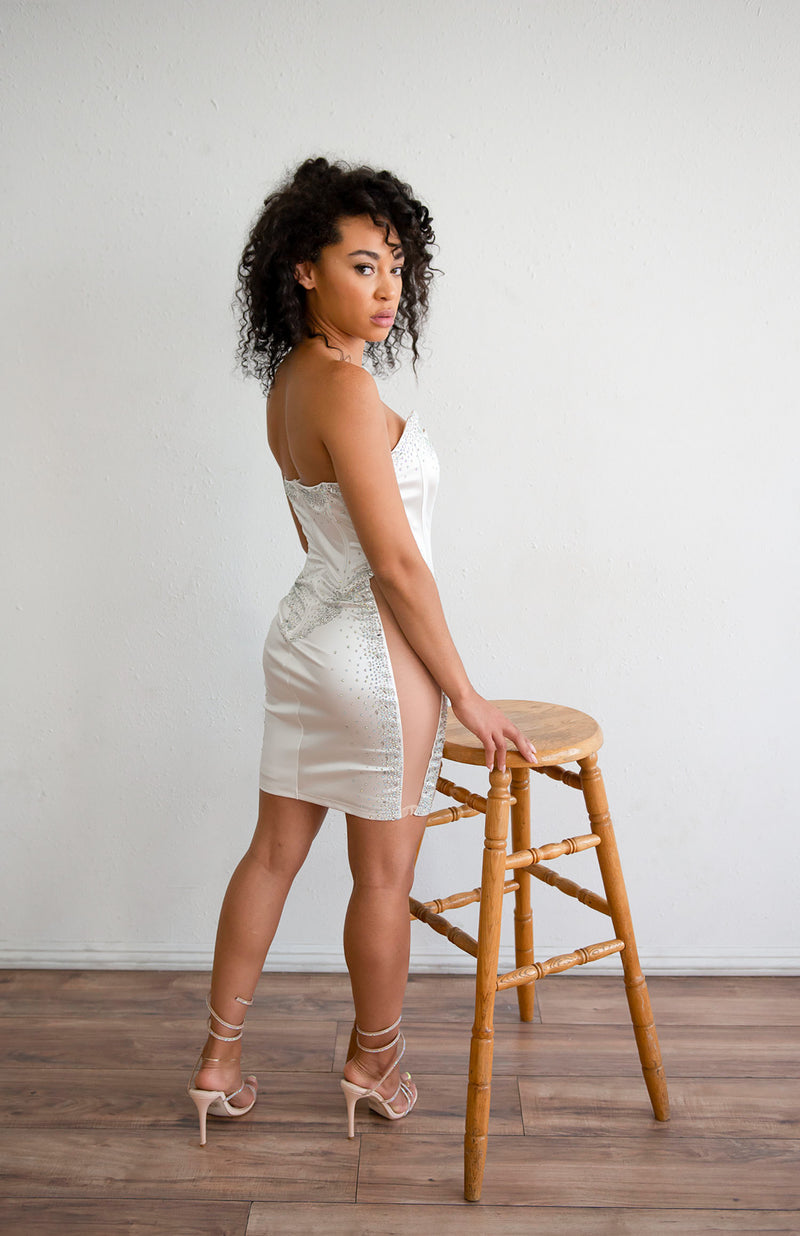 Strapless mini dress with deep v neck line, rhinestone details, and mesh sides in white.